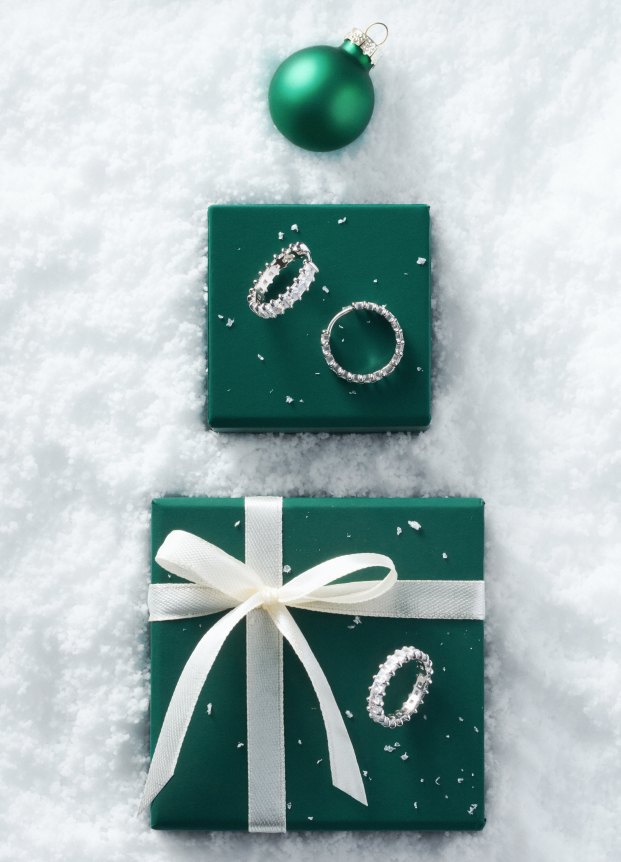 Diamond earrings on green gift boxes in snow