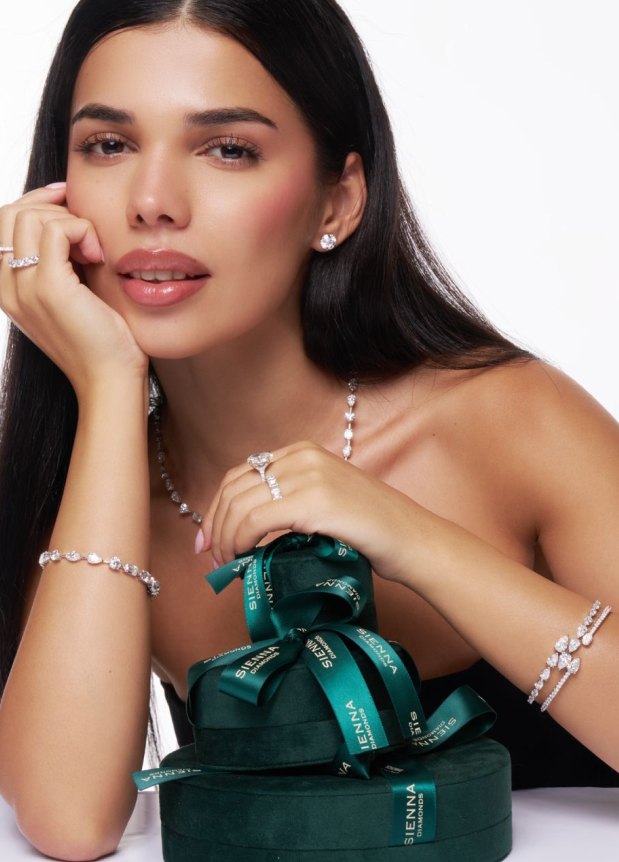 Model wearing diamond jewellery leaning on branded green gift boxes