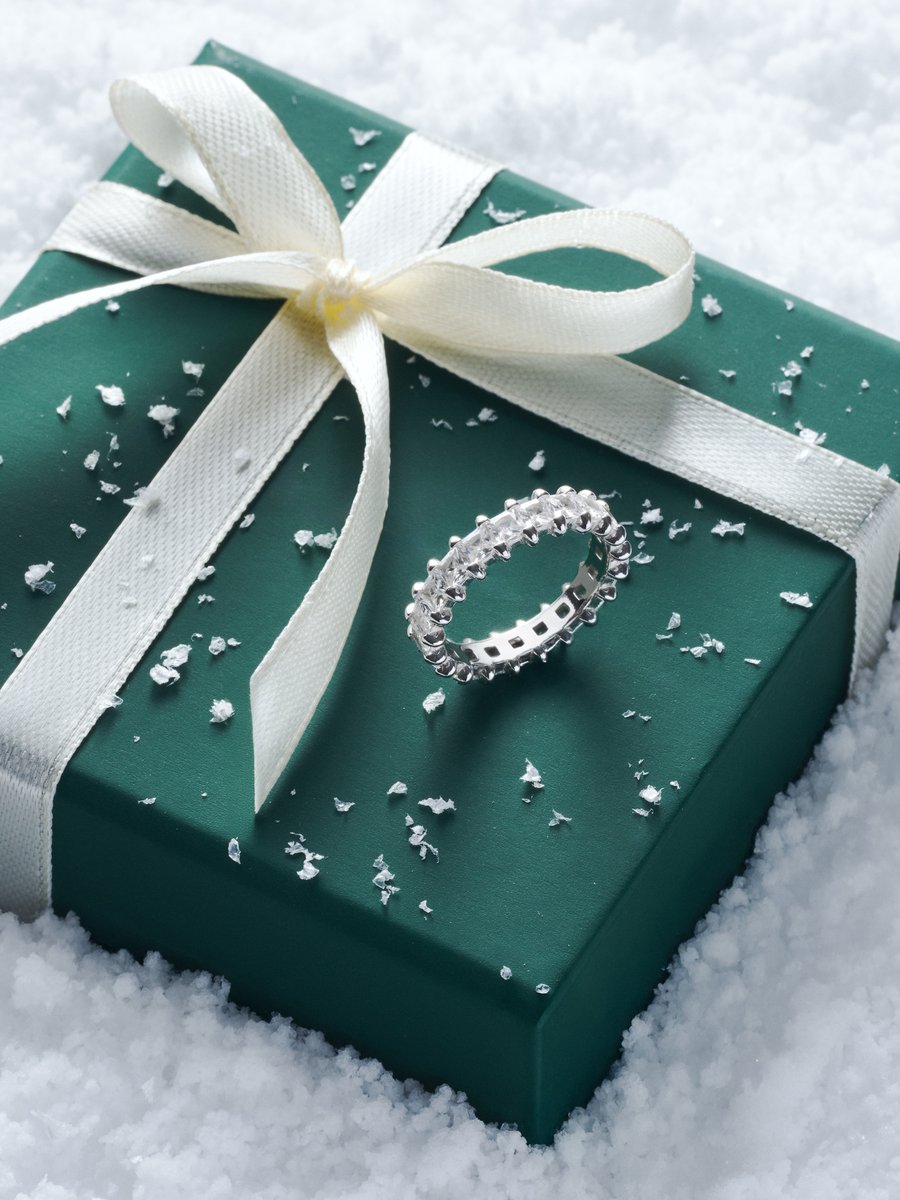 Diamond eternity ring on a green gift box tied with a cream ribbon