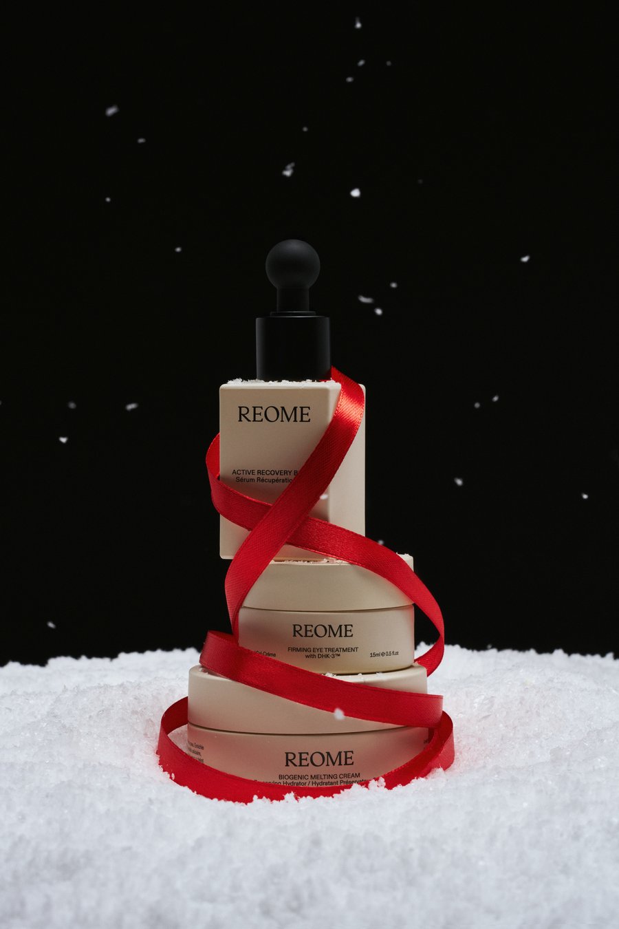 REOME skincare stacked and wrapped in red ribbon on snow
