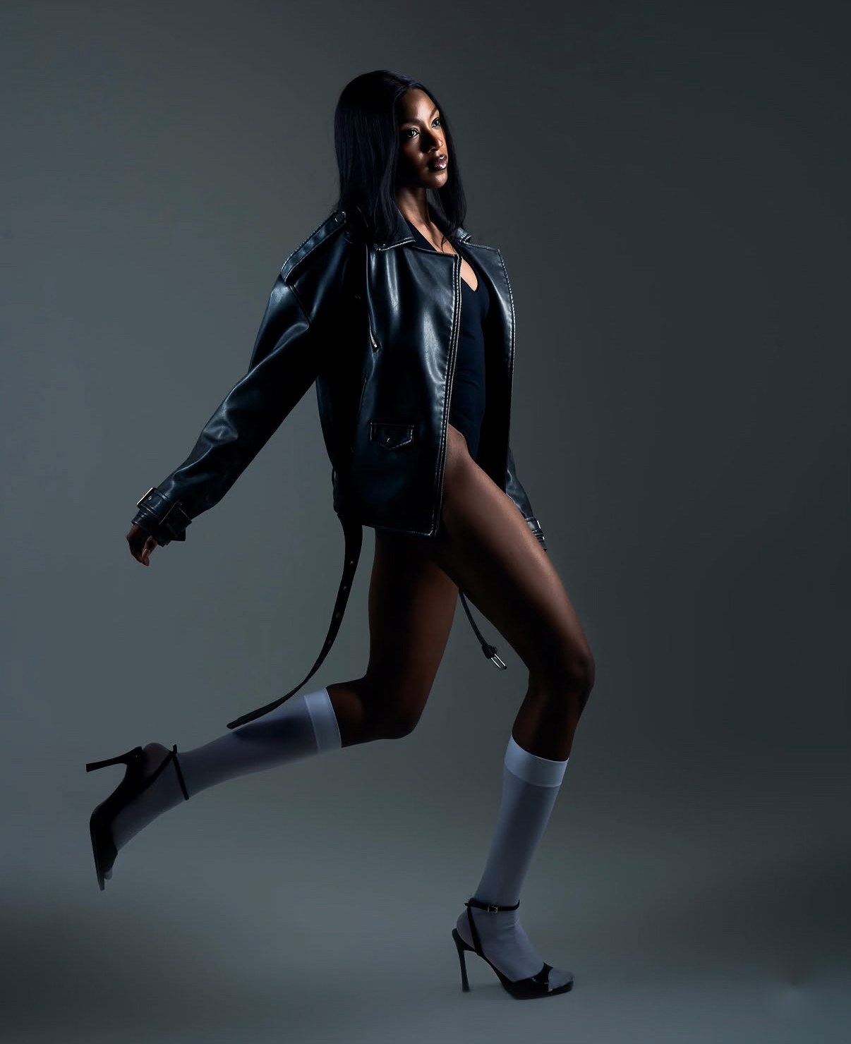 Model in a black leather jacket and white knee socks mid-stride, shot by a previous workshop participant