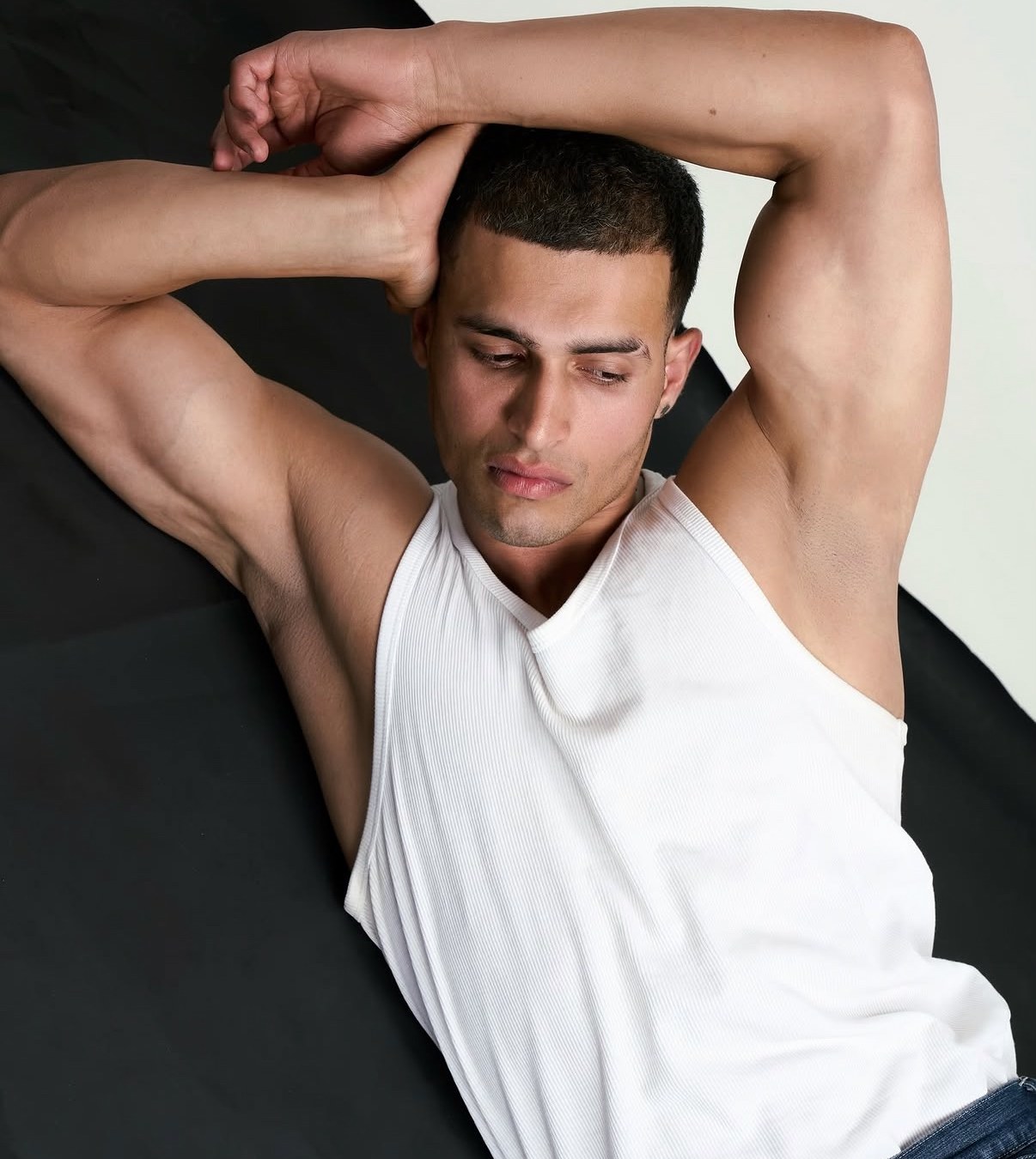 Male model in a white vest lying on black and white fabric, shot by a previous workshop participant