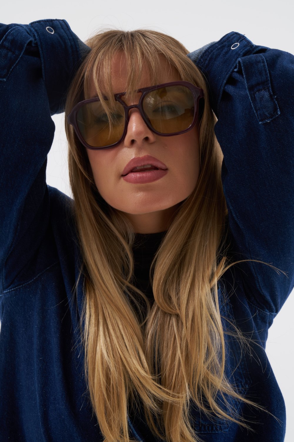 Close-up of a model in a denim shirt and tinted aviator sunglasses, shot by a previous workshop participant