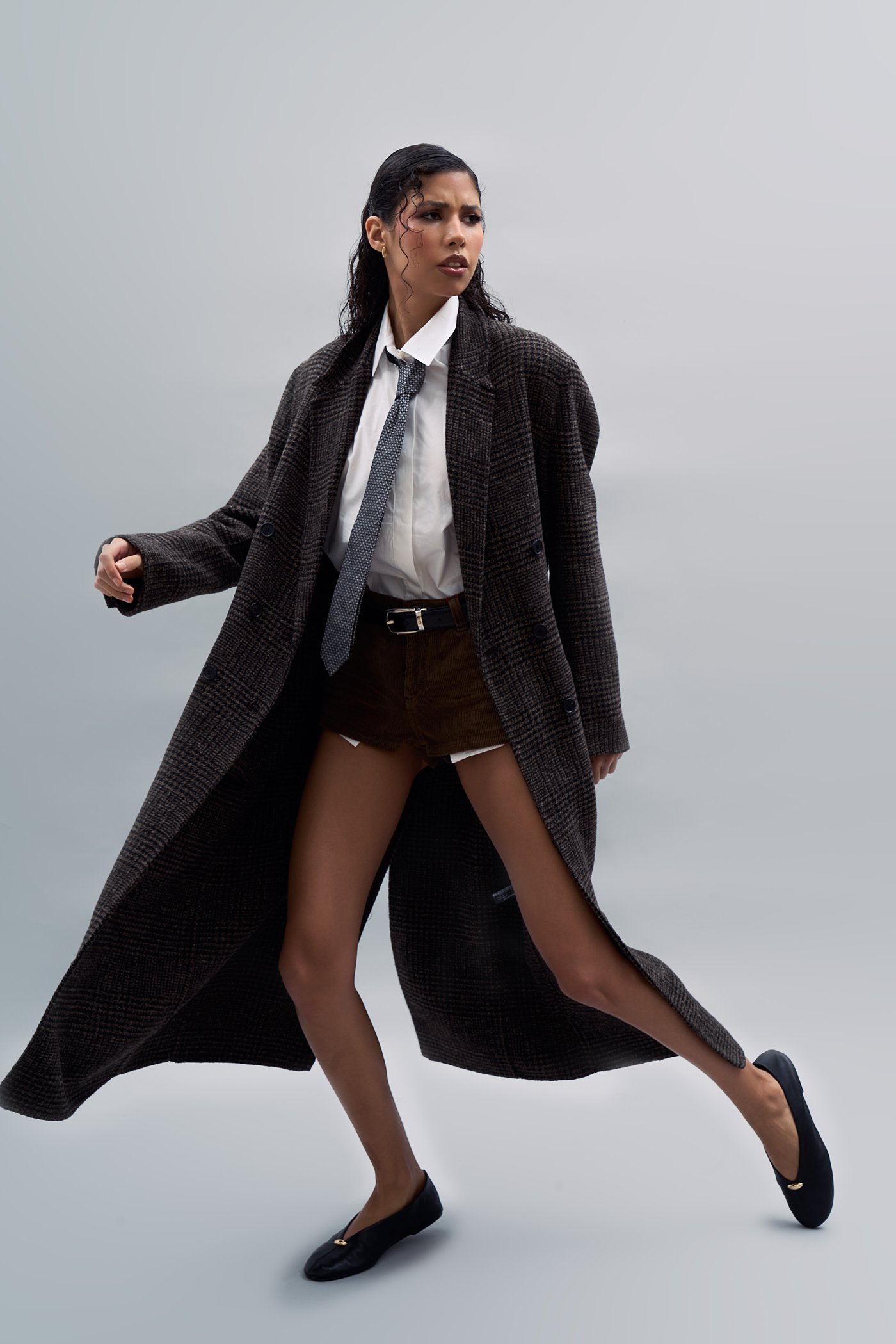 Full-length studio fashion shot of a model in a long tailored coat